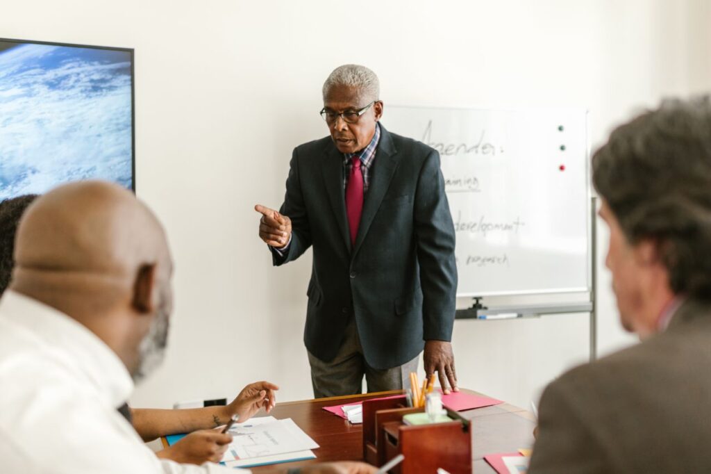 Senior man leading a business meeting with colleagues in a professional office setting.
